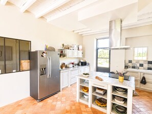 Una cocina moderna con armarios blancos, un refrigerador de acero inoxidable y un amplio ventanal que proporciona luz natural.