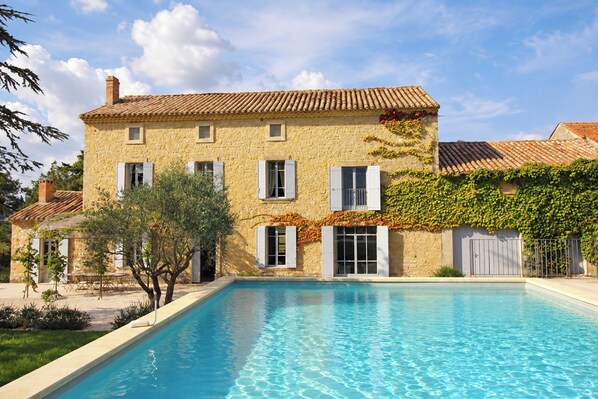 A two-story stone building with a swimming pool in front.