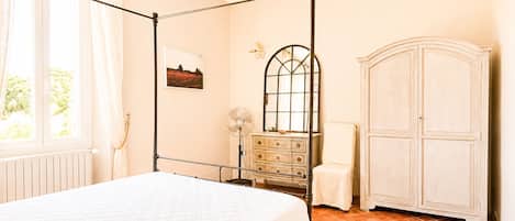 A bedroom with a four-poster bed, a dresser, a mirror, and a cabinet.