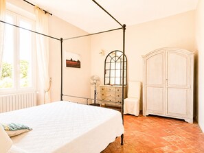 Une chambre à coucher avec un lit à baldaquin, une commode, un miroir et un placard.