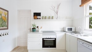 Una cucina compatta con mobili bianchi, forno integrato, microonde e lavello.