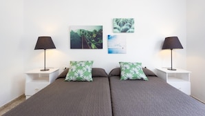 Una camera da letto con due letti, comodini bianchi e due lampade. In parete, tre quadri incorniciati.