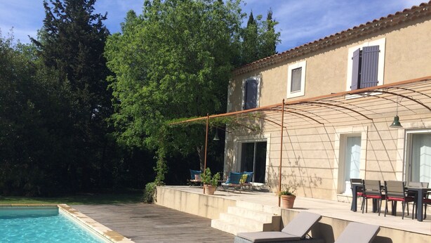 A poolside area with a wooden deck, lounge chairs, and a pergola. - Paradou quiet house with pool and garden near Les Baux de Provence (Paradou)