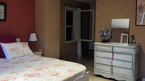 A bedroom with a bed, a dresser, a nightstand, a lamp, and a door leading to another room. - Paradou quiet house with pool and garden near Les Baux de Provence (Paradou)