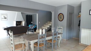 A dining area with a wooden table and chairs, a staircase, and a living room with a sofa and a fireplace. - Paradou quiet house with pool and garden near Les Baux de Provence (Paradou)