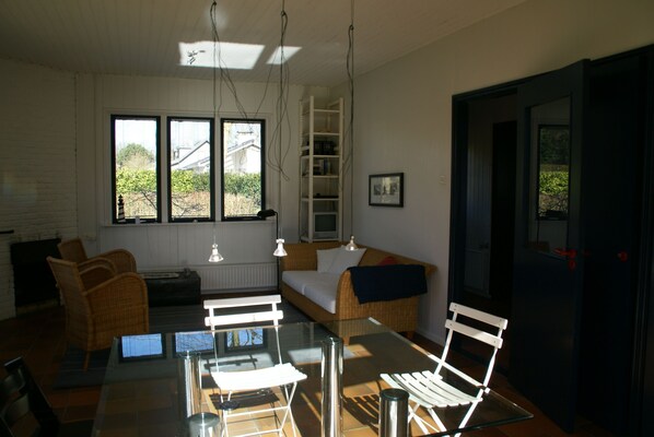 A room with a glass table, wicker furniture, a bed, and a view of the outside.