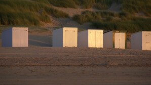 A row of beach huts with a sandy beach and dunes in the background. - Nice holiday home for 6 pers., Only 500m from the beach, with own beach cabin (Oostkapelle)