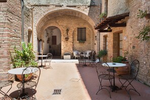 A courtyard with brick walls, arched doorways, and outdoor seating.