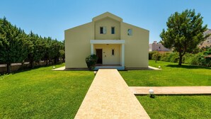 Une maison à deux étages avec un porche à l’avant, une allée pavée et une pelouse bien entretenue.