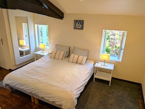 Un dormitorio con una cama grande, dos mesitas de noche, una ventana y un espejo.
