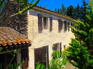 Un edificio tradicional con tejado de baldosas, contraventanas de madera y pared de piedra.