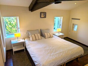 Een slaapkamer met een groot bed, twee nachtkastjes, een raam en een deur.