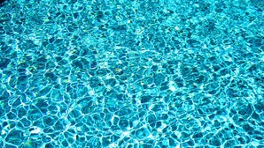 A clear view of a swimming pool's surface with visible ripples and reflections.