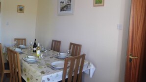 Un coin repas avec une table dressée pour quatre personnes, un canapé et une lampe.