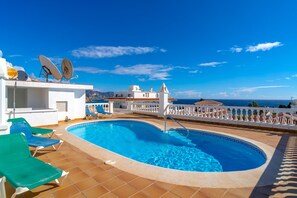 Une piscine sur le toit, avec une eau d’un bleu cristallin, entourée de murs blancs et d’une balustrade blanche.