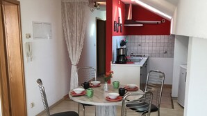 A compact kitchen with a dining area. It includes a round table with chairs, a coffee maker, and a sink.
