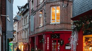 Een geplaveid straatje omzoomd door historische panden, waaronder een restaurant met een rode gevel en een winkel met etalage.