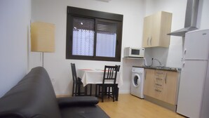 A compact living space with a sofa, a dining table with chairs, a washing machine, a microwave, and a refrigerator. - Nice loft in downtown Seville (Sevilla)