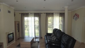 Un salon avec un canapé en cuir noir, une table basse en bois, un téléviseur et une cheminée.