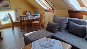 Ein gemütlicher Wohnbereich mit einer Couch, einem kleinen Holztisch und einem Esstisch mit Stühlen.