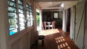 A spacious hallway with wooden flooring, large windows with white frames, and a view of a kitchen area. - CocosunLodge * superb sea view and private pool * (TROIS ILETS)