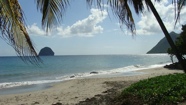 A beach with clear blue water, a sandy shore, and a mountain in the distance. - CocosunLodge * superb sea view and private pool * (TROIS ILETS)