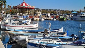 A marina with several boats docked, a carousel, and a clear sky.