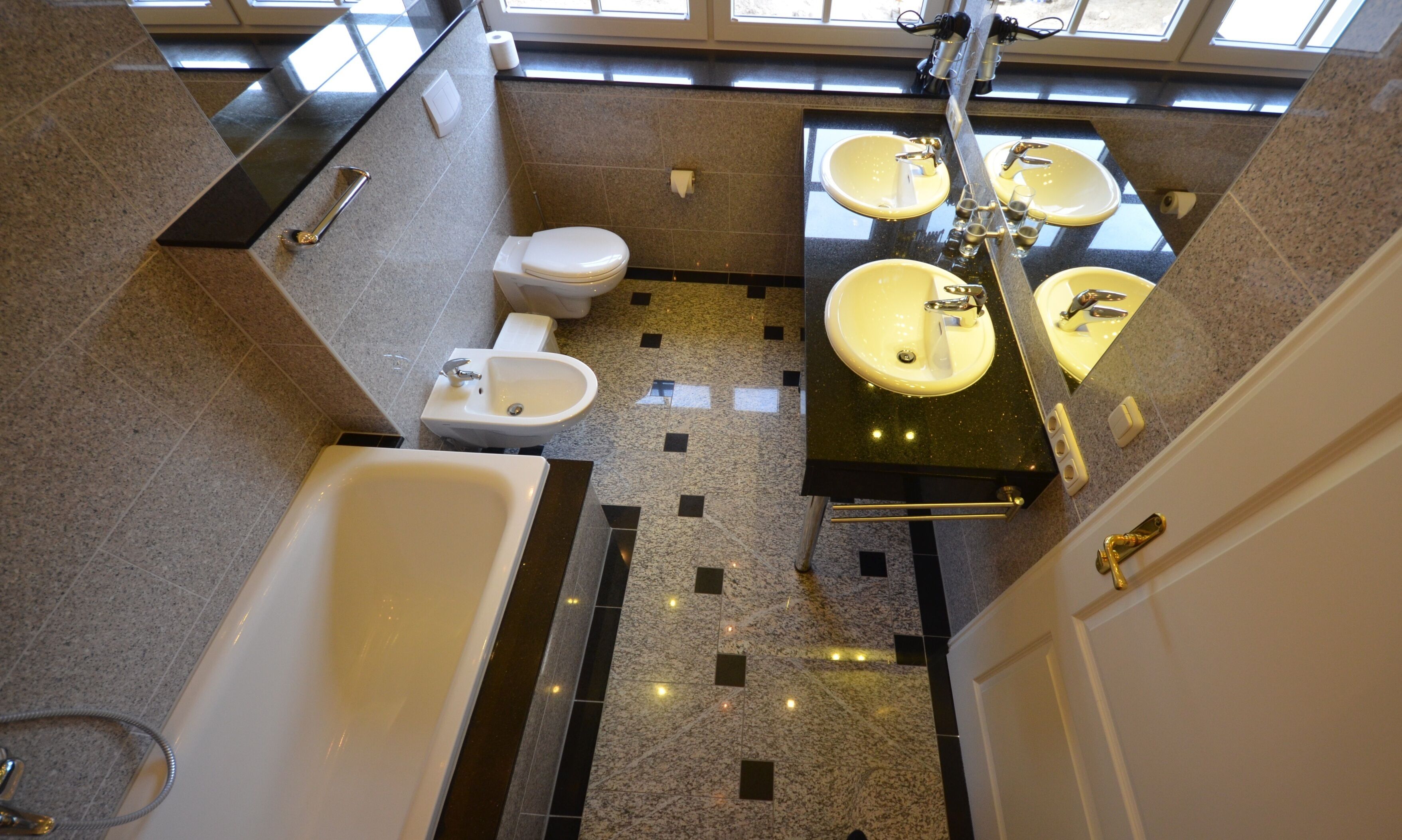 A modern bathroom with a bathtub, toilet, and two sinks with mirrors.