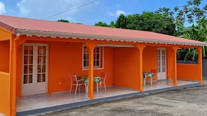 A bright orange building with a red roof, featuring a covered patio with two tables and chairs. - A rejuvenating stay in our peaceful gîtes (SAINTE ROSE)