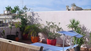 En tagterrasse med en træbænk, plantekasser og et blåt bord med solpanel.