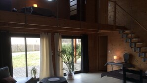 A spacious living area with a sofa, two round tables, a staircase, and a view of the outdoors.