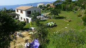 A white building with a balcony, surrounded by a grassy area with a view of the sea. - F3 of 80m ², swimming pool with sight on sea and mountains Arrival possible during the week (Calcatoggio)