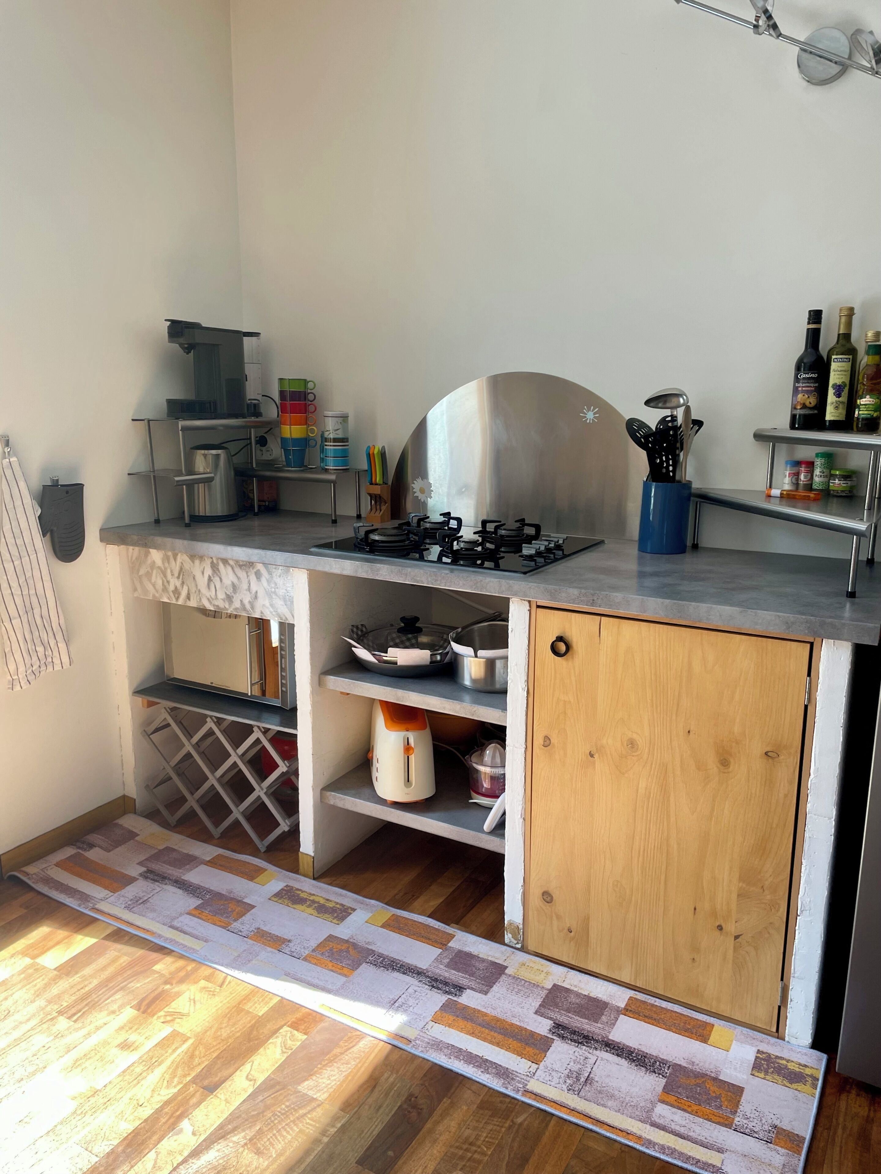 A compact kitchen with a gas stove, a coffee machine, and various kitchen utensils.
