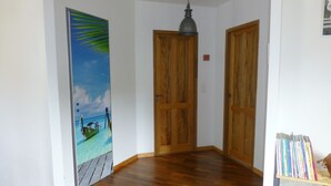 A hallway with wooden flooring, a wooden door, and a wall-mounted light fixture. - F3 of 80m ², swimming pool with sight on sea and mountains Arrival possible during the week (Calcatoggio)