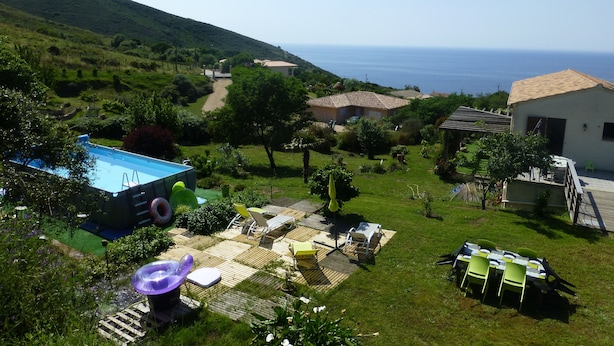 A pool area with a hot tub, lounge chairs, and a table set up for dining, overlooking a scenic view of the sea and hills. - F3 of 80m ², swimming pool with sight on sea and mountains Arrival possible during the week (Calcatoggio)