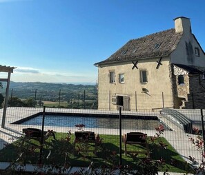 Un bâtiment en pierre doté d’une piscine et offrant une vue sur la campagne.