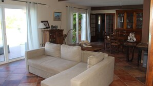 A living room with a beige sofa, a wooden cabinet, and a dining area with chairs and a table.
