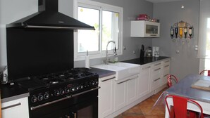 A kitchen with white cabinets, a black stove, and a window with a view of the outdoors.
