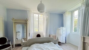 Et soveværelse med seng, kommode, spejl og et vindue.