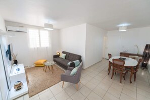 A modern living room with a sofa, armchair, coffee table, and dining table.