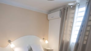 Una camera da letto con un letto, lampade da comodino, un tavolino, un tappeto e un condizionatore d'aria.
