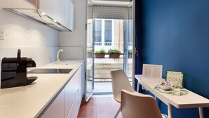 A modern kitchen with a built-in oven, a sink, and a dining area with a table and chairs. - COZY FIRST FLOOR IN THE HEART OF ORTIGIA (Siracusa)