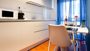 A modern kitchen with white cabinets, a microwave, and a dining area with a table and chairs. - COZY FIRST FLOOR IN THE HEART OF ORTIGIA (Siracusa)