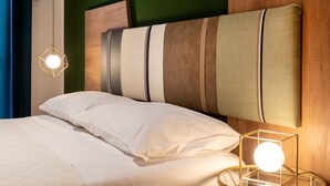 A neatly made bed with white linens, a wooden headboard, and a bedside table with a glass top and a round lamp. - COZY FIRST FLOOR IN THE HEART OF ORTIGIA (Siracusa)