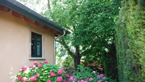 A house with a window and pink flowers in the garden. - Guest house "Living in the garden of the senses" (Kindenheim)