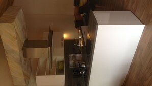 A modern kitchen with white cabinets, a stainless steel sink, and a coffee machine. - Guest house "Living in the garden of the senses" (Kindenheim)