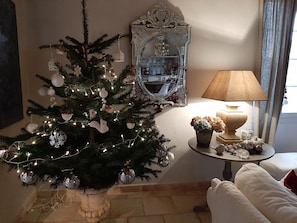 Una sala de estar con un árbol de Navidad, un espejo, una lámpara y una planta en maceta.