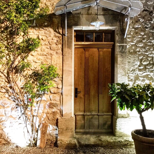 A stone building with a wooden door, a potted plant, and a small umbrella.
