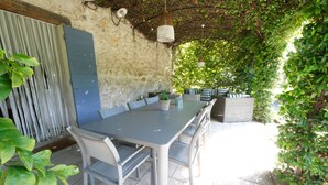 Un área de comedor al aire libre con un muro de piedra, una mesa metálica y sillas.
