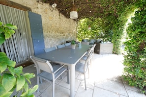An outdoor dining area with a stone wall, a metal table, and chairs. - Holiday rental CAUMONT SUR DURANCE LS6-248 (Caumont sur Durance)